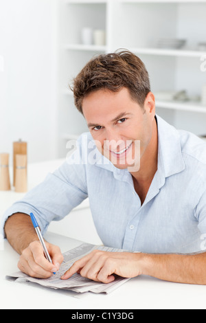 Kluger Mann tut eine kryptische Kreuzworträtsel sitzt in seiner Küche Stockfoto