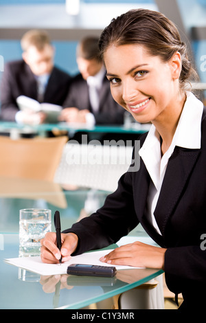 Portrait der schönen Frau Blick in die Kamera auf dem Hintergrund von zwei Geschäftsleuten im Konferenzraum Stockfoto