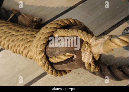 Detail von einem Schiffe rigging. Ein hölzerner Block und Hanf Seil gegen ein Teakdeck. Stockfoto