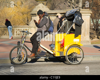 Rikscha-Fahrer im New Yorker Central Park prüft seine Nachrichten auf dem Handy Stockfoto