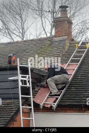 ARBEITER ARBEITEN VON LEITERN AUF INLÄNDISCHEN HAUS RE DACH REPARATUREN DIGITALUMSTELLUNG NEUE ANTENNEN SIGNAL ANALOGABSCHALTUNG ETC. UK Stockfoto