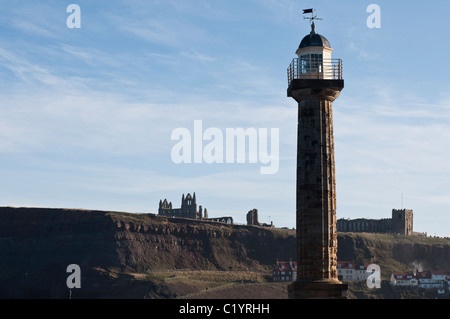 Ein Blick auf den Leuchtturm auf der Nordmole in Whitby, North Yorkshire, England mit zerstörte Whitby Abbey im Hintergrund. Stockfoto