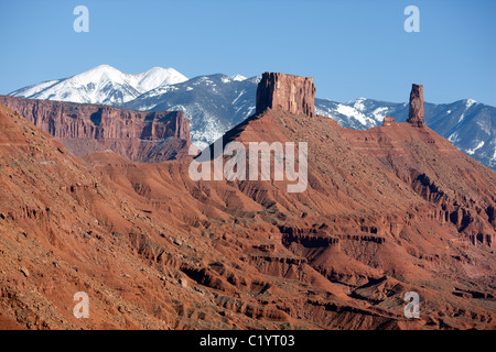 LUFTAUFNAHME. Monolithen aus rotem Sandstein im Castle Rock und schneebedeckten La Sal Mountains. Moab, Grand County, Utah, USA. Stockfoto