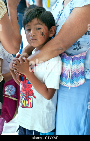 kleine mexikanische junge in Spiderman t-Shirt mit bemalten Spinne Tattoo auf seiner Wange sicher festhalten an seiner Mutter Oaxaca Mexico Stockfoto