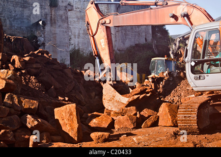 Löschen einer Baustelle Erdbewegung. Nachverfolgte Bagger im Vordergrund und Traktor-Lader-Bagger in der Ferne. Stockfoto