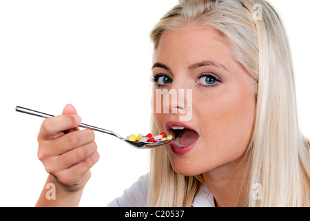 Frau mit vielen Pillen auf einem Löffel Stockfoto