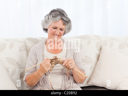 Ältere Frau stricken auf ihrem sofa Stockfoto