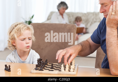 Kleiner Junge spielt Schach mit seinem Großvater Stockfoto