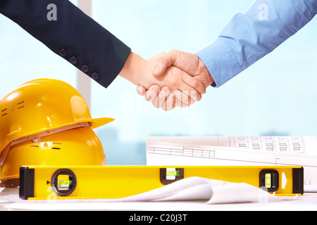 Nahaufnahme der Geschäft Leute Handshake über Helme, Dokumente, Arbeiter-tool Stockfoto