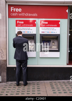 Mann am Handy bei HSBC Geldautomat der Strang-London Stockfoto