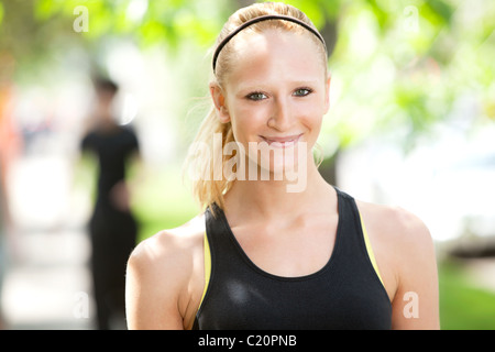 Nahaufnahme von einer hübschen Frau in Sportkleidung mit Freund im Hintergrund Stockfoto