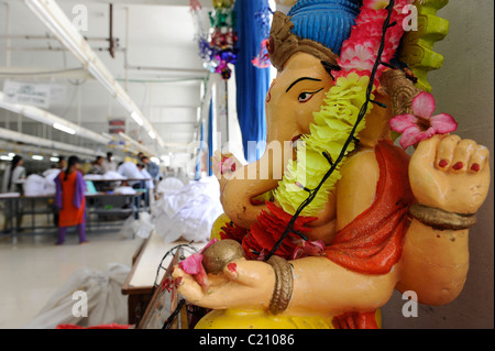 Indien, Tamil Nadu, Tirupur, Frauen arbeiten in Fair-Trade-Textil-Fabrik, Herstellung von Kleidung und Bekleidung für den Export, hindu-Gott Ganesha als Glücksbringer Stockfoto