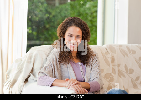 Lächelnde Frau sitzen auf ihrem sofa Stockfoto