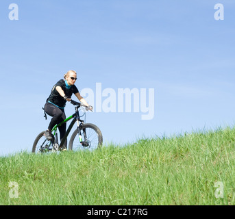 Frau auf einem Mountainbike über blauen Himmel Stockfoto