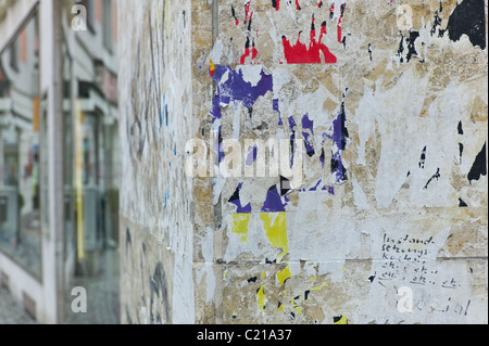 Wand eines Hauses mit bunten Resten der Plakate und Aufkleber drauf, München Stockfoto