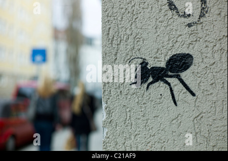 Graffiti zeigt eine Schwarze Ameise an der Ecke einer weißen Wand in München, Deutschland Stockfoto