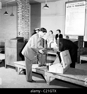 1950, historisch, lässt ein neu eingetroffener Besucher aus Übersee in Großbritannien seinen Koffer von einem uniformierten Zollbeamten, England, Großbritannien, überprüfen. Stockfoto