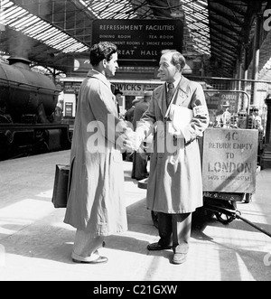 1950, historisch, begrüßt ein Beamter des British Council einen neu angekommenen männlichen Einwanderer auf einer Plattform am Bahnhof Euston, London, England. Stockfoto