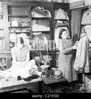 1950er Jahre, historisch, in einer Kostümabteilung, eine Frau und eine junge Dame, die an Theaterbekleidung arbeiten, in diesem Bild von J Allan Cash. Stockfoto