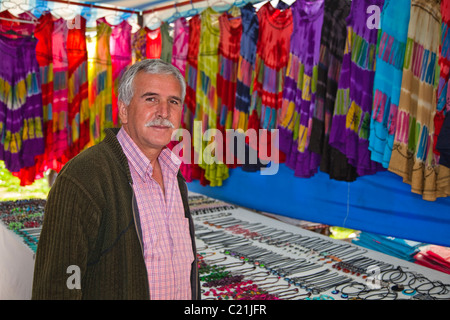 Türkischer Mann verkaufen Bekleidung und Stoffe auf einem Basar in Belek, Antalya, Türkei Stockfoto