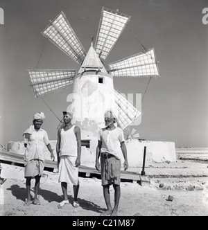 Aden, 1950er Jahre. Drei Arbeiter stehen vor einer alten Windmühle an einer Salzpfanne, Aden, in diesem historischen Bild von J Allan Cash. Stockfoto