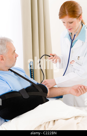 Krankenhaus - Arzt Check Blutdruck des Patienten mit gebrochenen arm Stockfoto