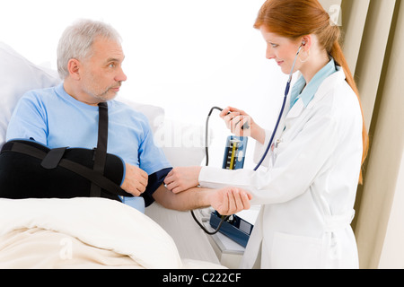 Krankenhaus - Arzt Check Blutdruck des Patienten mit gebrochenen arm Stockfoto