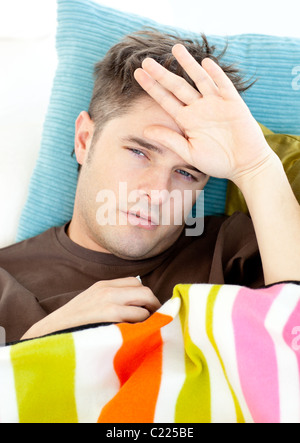 Kranker junge Mann Gefühl seine Temperatur lag auf dem sofa Stockfoto