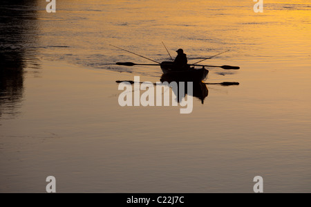 Fischer, die bei Sonnenuntergang am Fluss Oulujoki Finnland von einem Ruderboot / Schiff / Beiboot aus fahren Stockfoto