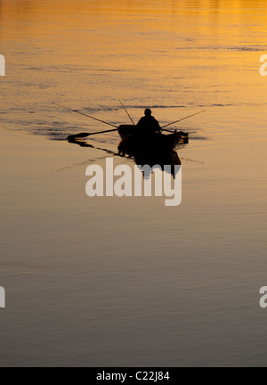 Fischer, die bei Sonnenuntergang am Fluss Oulujoki Finnland von einem Ruderboot / Schiff / Beiboot aus fahren Stockfoto