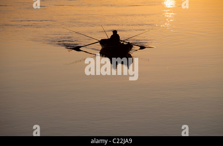 Fischer, die bei Sonnenuntergang am Fluss Oulujoki Finnland von einem Ruderboot / Schiff / Beiboot aus fahren Stockfoto