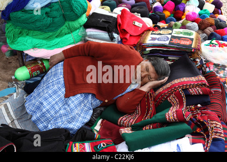 Quechua-Dame mit einem Nickerchen auf Textilien in Chinchero Markt, Sacred Valley, in der Nähe von Cusco, Peru Stockfoto