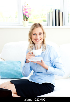 Geschäftsfrau Kaffeetrinken auf einem Sofa sitzt lächelnd Stockfoto