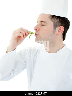 Charmante junge Koch mit geschlossenen Augen halten eine Kraut vor weißem Hintergrund Stockfoto