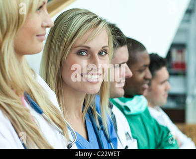 Porträt der Ärztin lächelt in die Kamera mit ihrem Team in einer Linie auf Treppe Stockfoto
