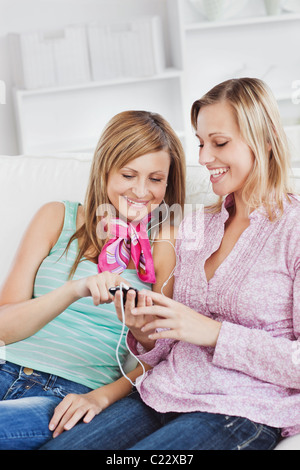 Zwei strahlende Frauen Musikhören mit Kopfhörer mit ihrem Handy Stockfoto