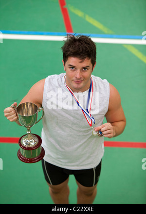 Glücklicher junge Mann hält einen Pokal und eine Medaille Stockfoto