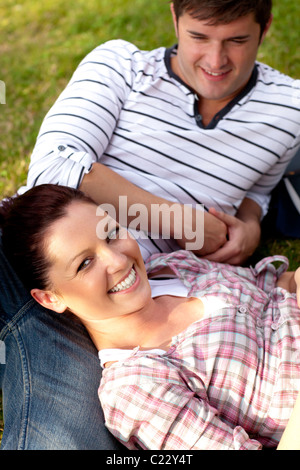 Freudige paar Studenten sitzen auf Rasen und lächelt in die Kamera Stockfoto