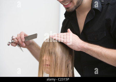 Mann schneiden und Kämmen eine junge Womans Haare in der Friseure Stockfoto