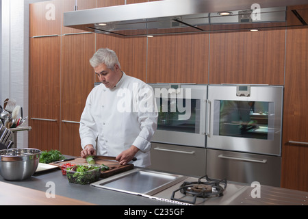 Mitte-Adult-Koch bereitet Salat Stockfoto