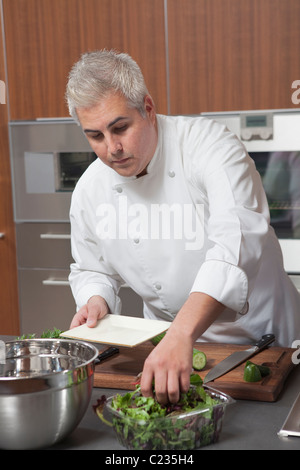 Mitte-Adult-Koch bereitet Salat Stockfoto