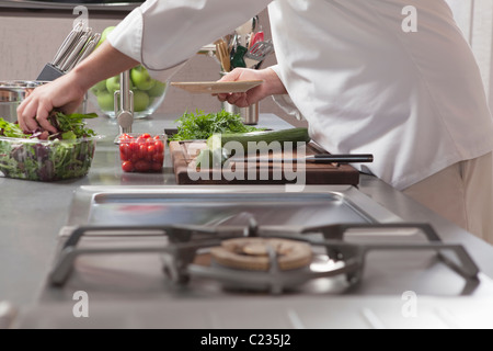 Mitte-Adult-Koch bereitet Salat Stockfoto