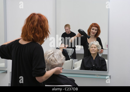 Stylist Schlag-trocknet ältere Frau an den Haaren Stockfoto