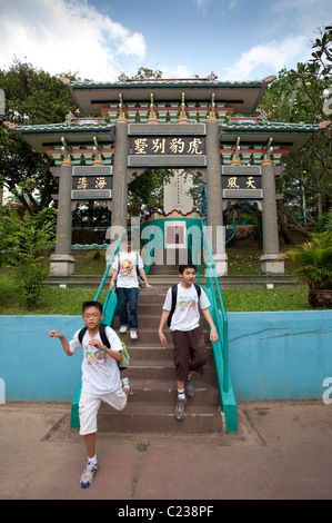 Drei asiatische Jungs auf Schritte erkunden die ungewöhnliche Haw Par Villa Themenpark in Singapur Stockfoto