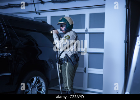 Nightwatch Streifenpolizist prüft Luxusauto in garage Stockfoto