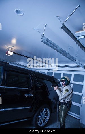 Nightwatch Streifenpolizist prüft Luxusauto in garage Stockfoto