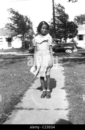 Sehr hübsches junges schwarzes Mädchen mit dem Familienauto im Hintergrund, Posen vor ihrem Haus in Washington Vororten, um 1950, USA Stockfoto