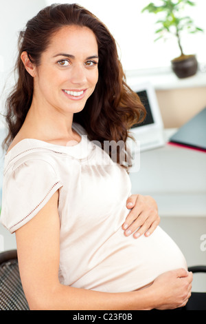 Schwanger Geschäftsfrau lächelnd in die Kamera sitzt an ihrem Schreibtisch Stockfoto