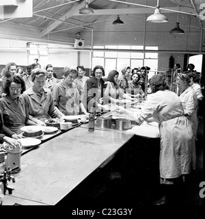 der 1950er Jahre. England.  Arbeitnehmerinnen Line-up um ihr Mittagessen in der Kantine immer bereit Batteriefabrik bedient zu werden. Stockfoto