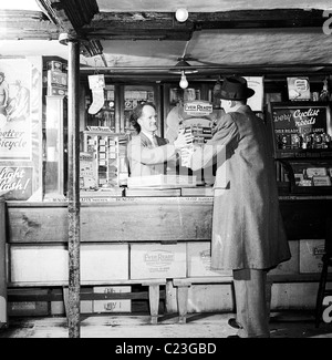 England der 1950er Jahre. Verkäufer für die Firma jemals bereit Batterie liefert die Ware an einen Fahrrad-Shop-Kunden. Stockfoto